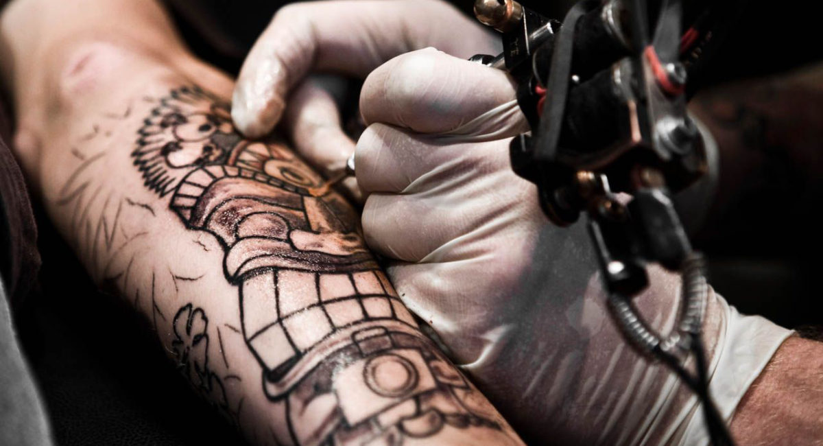 imagen de tatuador trabajando el brazo de cliente